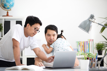 Asian modern family and little girl ,while dad works with notebook on work table at home office. の写真素材
