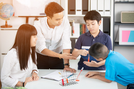 Portrait of asian man teacher and students scientists making experiment in classroom