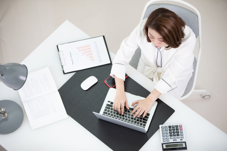 Happy young asian woman at the office set up using modern technology.の写真素材