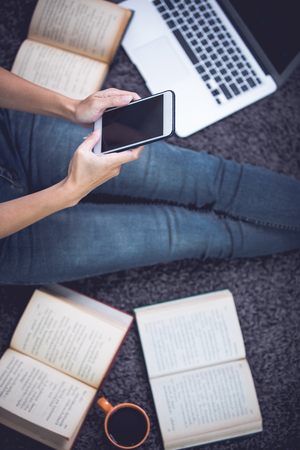 Woman sitting and relaxing on carpet using devices, phone, computer notebook and laptop, lifestyle and work at home conceptの写真素材