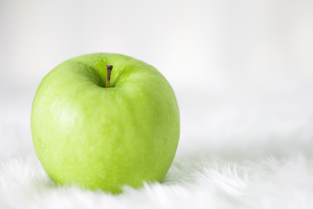 Green apple on white carpet with copy space .の写真素材