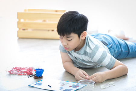 Happy asian boy lying and playing plastic block at homeの写真素材