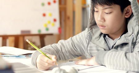 Cute asian teen boy doing your homework at home.の写真素材