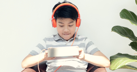 Cute asian boy watch and playing on tablet computer with happy face.の写真素材