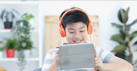 Asian pre teens playing tablet computer with smile face at home.