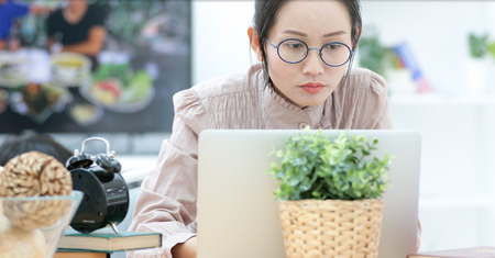 Asian woman working on laptop at home .