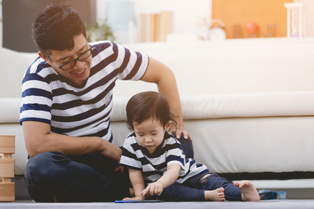 VIew of a Father and his little daughter using mobile at home .の写真素材
