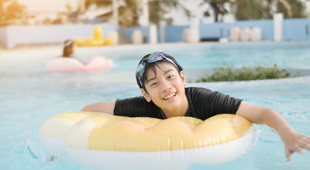 Happy asian child playing in swimming pool with smile faceの写真素材