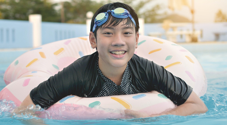 Happy asian child playing in swimming pool with smile faceの写真素材