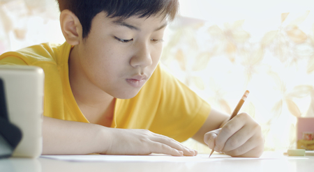 Child writes homework. Children to doing home works on table in living roomの写真素材