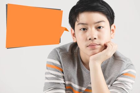 Photo of un happy boy looking at camera with orange dialog box isolated over gray background.