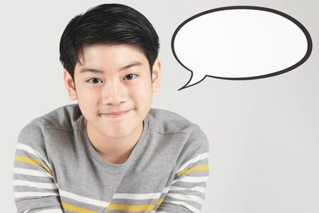 Photo of asian happy boy looking at camera with dialog box isolated over gray background.