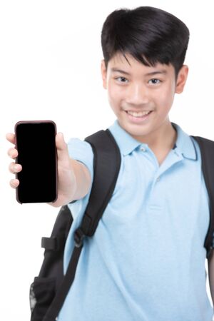Asian student boy with backpack and stationery holding cell phone isolated on white background. Back to school concept.の写真素材