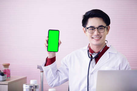 Young doctor showing a phone with smile face in office. Green screen conceptの写真素材