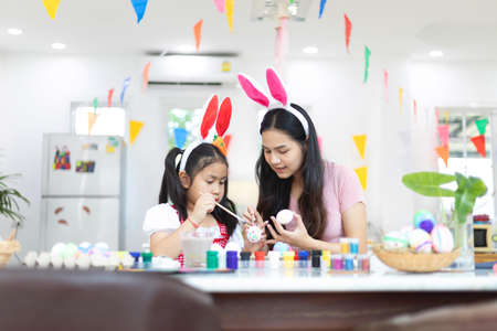 Attractive young woman with little cute girl are preparing for Easter celebration. Mom and daughter...