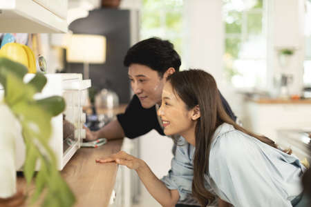 Asian couple Help each other to make a bakery In a romantic atmosphere in the kitchen at home. Young...