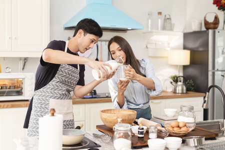 Asian couple Help each other to make a bakery In a romantic atmosphere in the kitchen at home. Young...