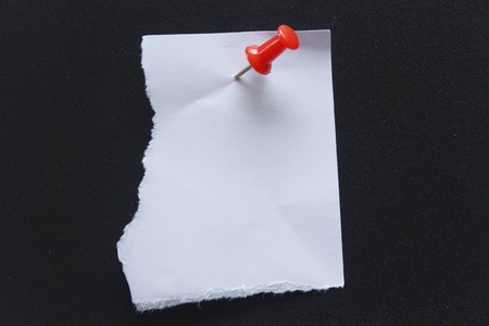 white paper note with red pushpin on black background