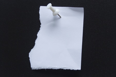white paper note with white pushpin on black backgroundの写真素材