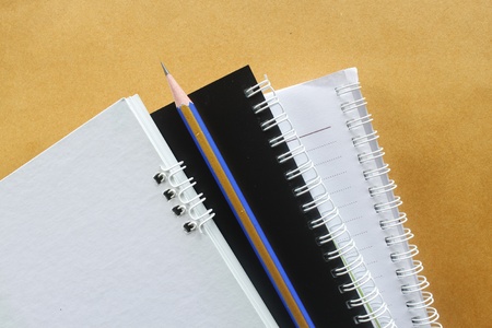 3 notebook one pencil on brown backgroundの写真素材