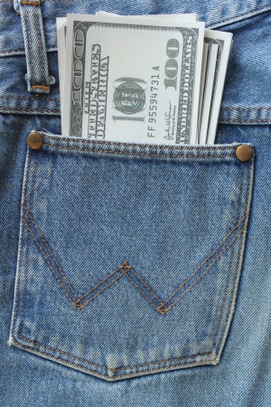 pocket money. new dollar  in hip pocket of worn blue jeans close-up.の写真素材