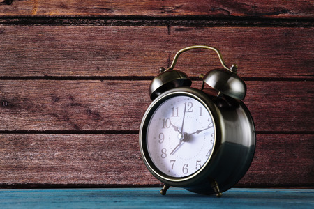 Alarm Clock stand over Wooden Wall