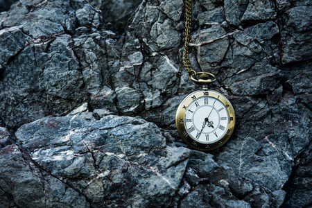 vintage golden pocket watch on rock background, time conceptの写真素材