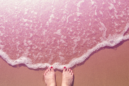 Red nail Feet of female stand on the summer sand beach with filter effect color, top view, Woman solo travel conceptの写真素材