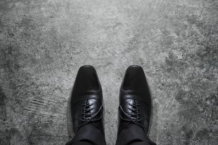 Black formal shoes of businessman standing over dark grunge cement floor with plenty for copy space, top viewの写真素材