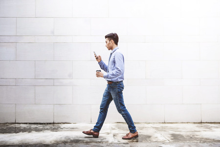 Young motivation Businessman use smart phone while walk outdoor building, Lifestyle of modern male to communicate, message or technology in business conceptの写真素材