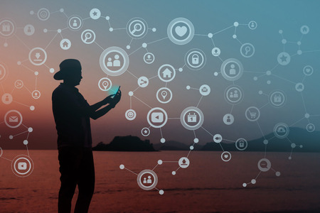Always Connected concept, Silhouette of Young human using smart phone to Communicate in Network, Beach or Countryside as backgroundの写真素材