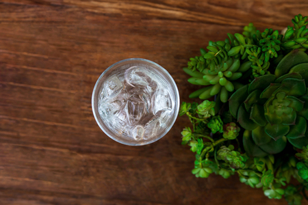Glass of Cold Water with Ice on Wooden table, Top view, Green Leaf are Decoratedの写真素材