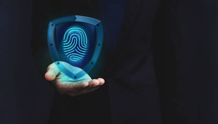 Network Security System Concept, Fingerprint inside a Shield Guard to Protected Identify of User or Personal Information, Present over Businessman Hand, Dark light and Modern Transparent styleの写真素材