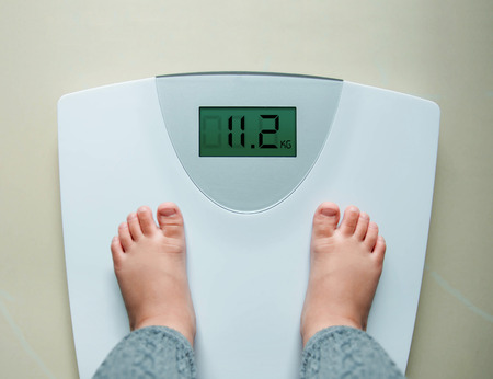 Healthy Weight Gain for Baby or Children Concept, A 2 Years Old Kid Standing on Weight Scales, Top...
