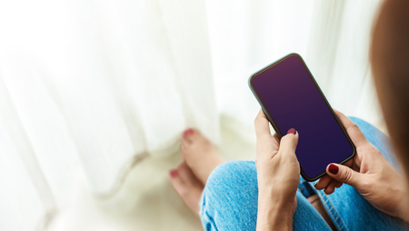 Smart Phone Mockup. Mobile Screen as Clipping Path. Top view. Woman using phone in Houseの写真素材