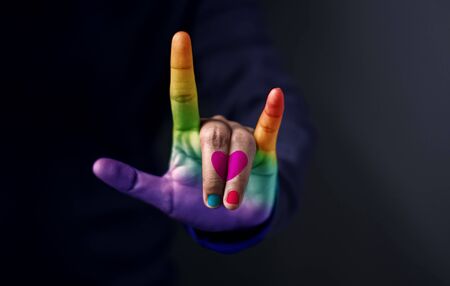 Love for Gay and Homosexual Concept, Midsection Of Man With Colorful Hand Guesture in means "I Love You" with Heart and Rainbow Color Against Dark Backgroundの写真素材