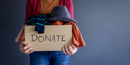 Donation Concept. Woman holding a Donate Box with full of Clothesの写真素材