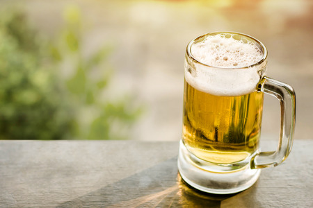 Drinking Beer in Summer Concept. Glass of Beer on Balcony. Natural Sunlight and Tree as background, Warm Toneの写真素材