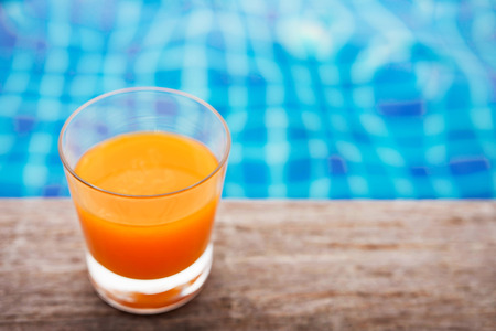 Relaxation with Orange Juice at the Poolside in Summer, Blue Turquoise Pool as background. Top View...