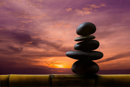 Balance Concept between of Life and work present by Natural Zen Rock Stack on Bamboo Wooden, Sunrise or Sunset Sky as backgroundの写真素材