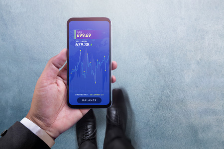 Investment and Analysis concept. Top View of Businessman Walking and holding Smartphone with Chart...