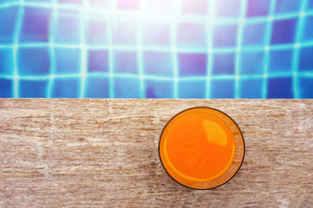 Summer Drink at the Swimming Pool. Glass of Orange Juice on the Poolside. Relaxation on Vacation or...
