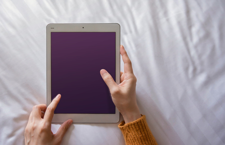 Mockup image of Digital Tablet. Woman Lay on Bed to using Tablet. Relaxing in the Morning. Top View, Screen as Clipping Pathの写真素材