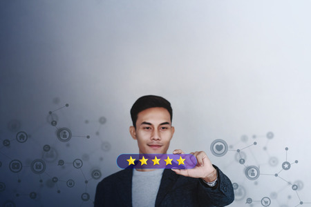 Customer Experience Concept. Young Businessman with Happy Face Showing Five Star Services Rating Satisfaction on Card. Happy Client's Feedback and Online Review. Surrounded by Network Iconsの写真素材