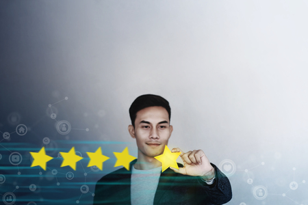 Customer Experience Concept. Young Businessman with Happy Face Showing his Five Star Services Rating Satisfaction. Happy Client's Feedback and Online Review. Surrounded by Network Iconsの写真素材