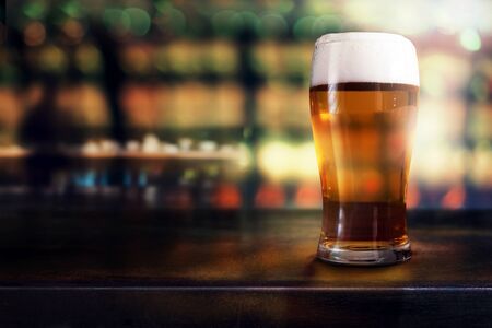 Glass of Beer on Table in Bar or Restaurant. Side View. Night Scene