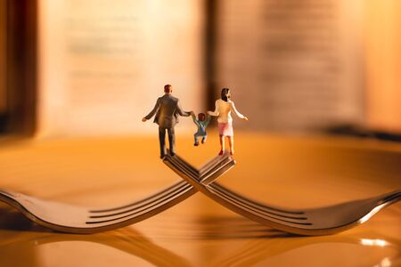 Happy Family and Work Life Balance Concept. Miniature of Father, Mother and Son holding Hands and Walking on the Fork in the Restaurantの写真素材