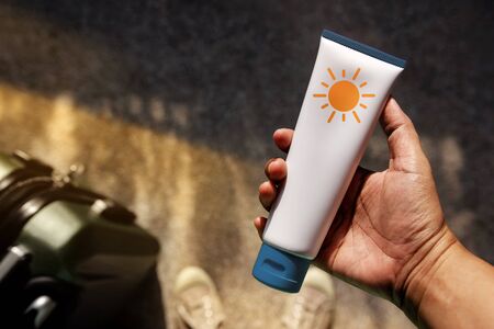 Young Person Holding a Sunscreen Lotion before Outing. Skincare concept. Top View, Grunge Dirty...