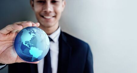 Globalization and Worldwide Concept. Happy Smiling Professional Businessman holding a Transparent Blue World Globe in Handの写真素材