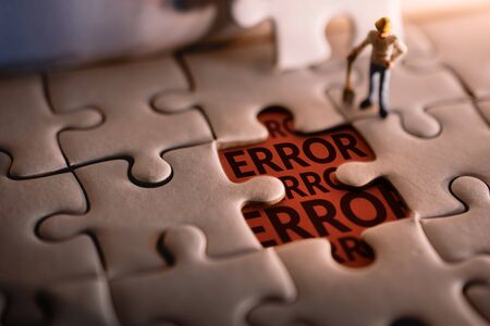 Solution Solving Problem Concept. a Miniature Worker Man Found Error Message on a Piece of Jigsaw Puzzleの写真素材